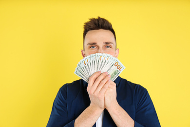 Happy man with cash money on yellow background