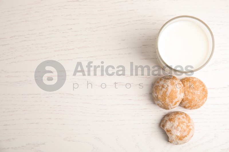 Photo of Tasty homemade gingerbread cookies and glass of milk on white wooden table, flat lay. Space for text