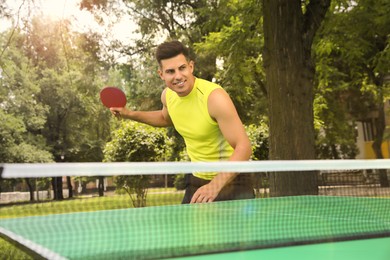 Man playing ping pong in park on summer day