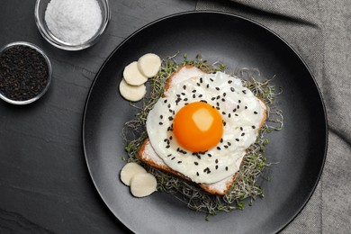 Tasty toast with egg, cheese and microgreens on black table, top view