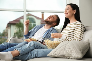 Happy couple watching movie with popcorn at home