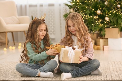 Photo of Cute little girls with Christmas gifts at home