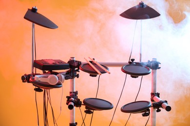 Modern electronic drum kit and smoke on orange background. Musical instrument