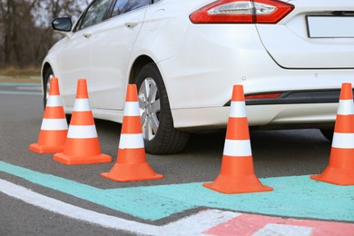 Modern car on driving school test track with traffic cones