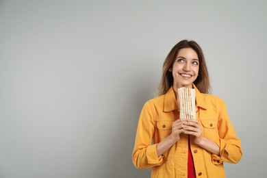Photo of Young woman with delicious shawarma on grey background, space for text