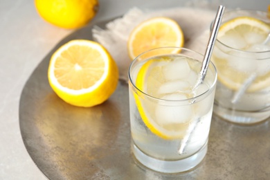Soda water with lemon slices and ice cubes on silver tray