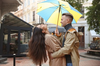 Photo of Lovely young couple with umbrella together under rain on city street
