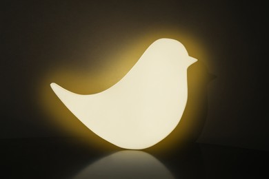Bird shaped glowing night lamp on black background