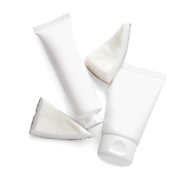 Tubes of hand cream and coconut pieces on white background, top view