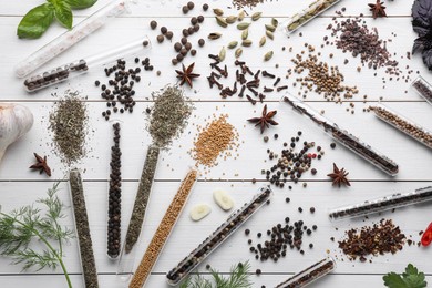 Flat lay composition with various spices, test tubes and fresh herbs on white wooden background