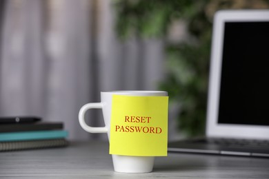 Sticky note with phrase Reset Password on cup indoors