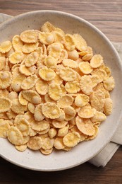 Photo of Bowl of tasty corn flakes on wooden table, top view