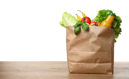 Paper bag with vegetables and bottle of juice on table against white background. Space for text