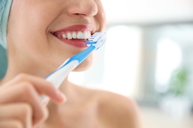 Young woman with toothbrush on blurred background, closeup. Space for text