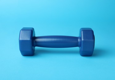Stylish dumbbell on light blue background, closeup