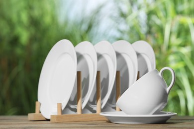 Photo of Set of clean dishware on wooden table against blurred background