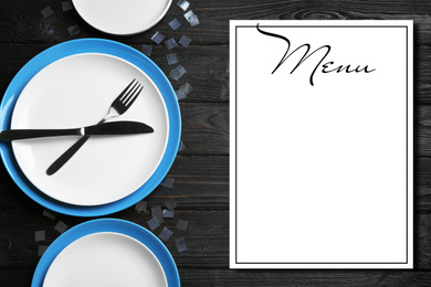 Elegant table setting and empty menu on black wooden background, flat lay. Space for text