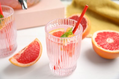 Photo of Delicious refreshing drink with grapefruit and mint on white table