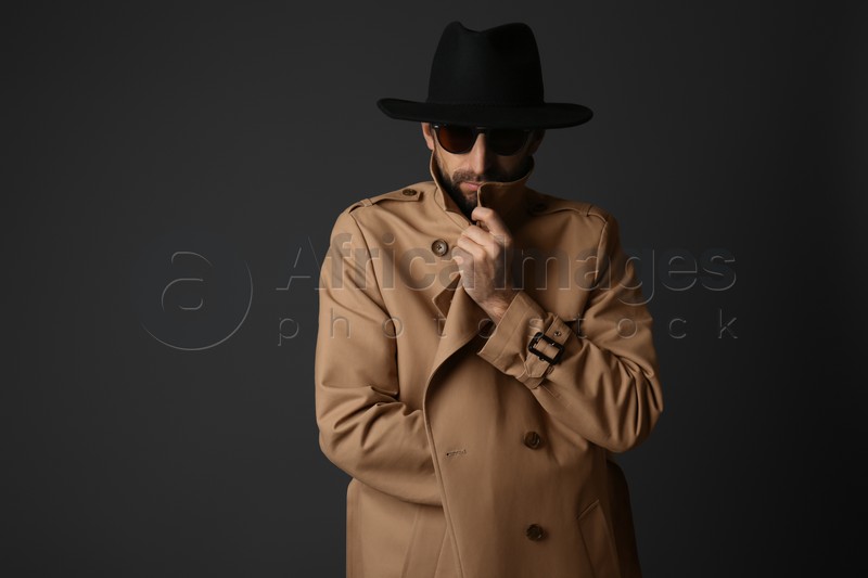 Exhibitionist in coat and hat on black background