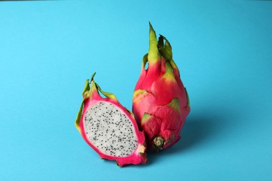Photo of Delicious cut and whole white pitahaya fruits on light blue background