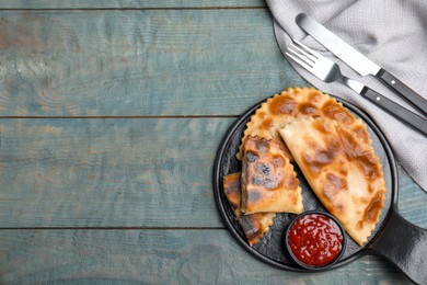 Delicious fried chebureki with ketchup served on light blue wooden table, flat lay. Space for text