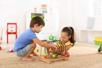 Cute little children playing with bead maze on floor at home. Educational toy