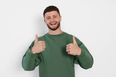 Young man showing thumbs up on white background