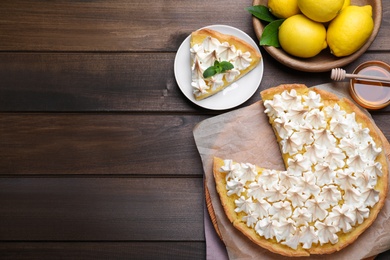 Cut delicious lemon meringue pie served on wooden table, flat lay. Space for text
