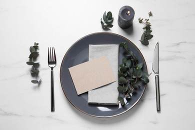 Photo of Stylish setting with cutlery, eucalyptus leaves and blank card on white marble table, flat lay. Space for text