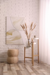 Fluffy reed plumes and painting in stylish room interior