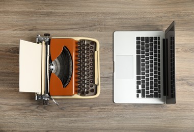 Old typewriter and laptop on wooden table, flat lay. Concept of technology progress
