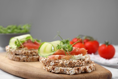 Crunchy buckwheat cakes with cream cheese, prosciutto and cucumber slices on wooden board, closeup