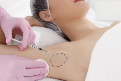 Cosmetologist injecting young woman's armpit, closeup. Treatment of hyperhidrosis