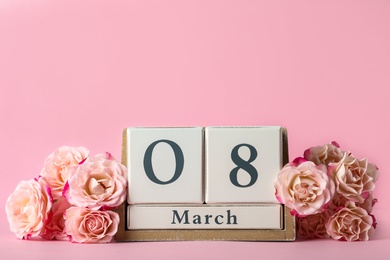 Wooden block calendar with date 8th of March and roses on pink background, space for text. International Women's Day