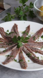 Photo of Plate with anchovy fillets and parsley on table, closeup