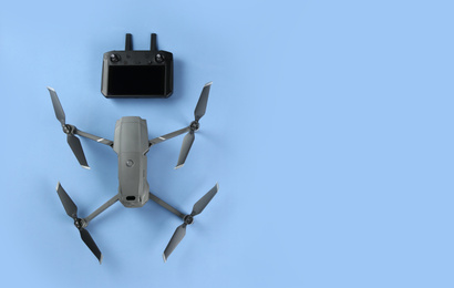 Modern drone with controller on blue background, flat lay. Space for text