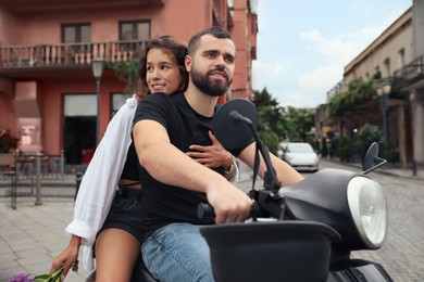 Beautiful young couple riding motorcycle on city street
