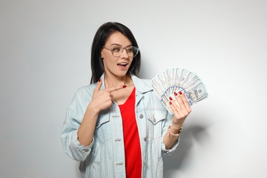 Portrait of stylish woman with money fan on light background