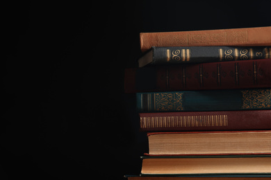 Collection of different books on dark background. Space for text