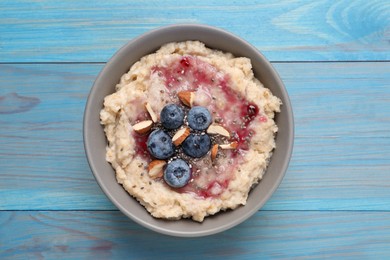 Tasty oatmeal porridge with toppings on light blue wooden table, top view