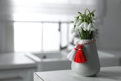 Beautiful snowdrops with traditional martisor on table indoors, space for text. Symbol of first spring day