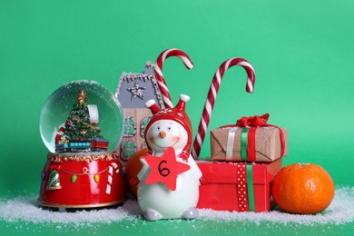 Decorative snowman with paper tag, gift boxes and festive decor on green background. December, 6 - Saint Nicholas Day