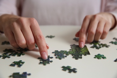 Young woman playing with puzzles at table, closeup