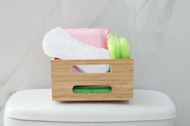 Organizer with different feminine hygiene products on toilet bowl in bathroom