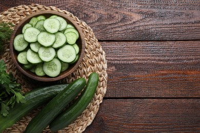 Fresh ripe cucumbers, dill and parsley on wooden table, top view. Space for text