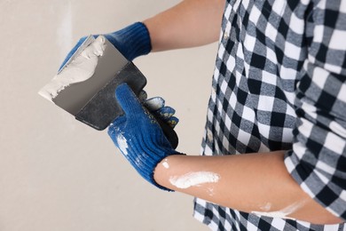 Worker with putty knives and plaster indoors, closeup. Home renovation