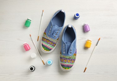 Amazing customized shoes and painting supplies on white wooden background, flat lay