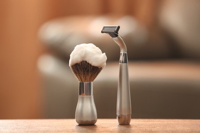 Shaving brush and razor on table against blurred background