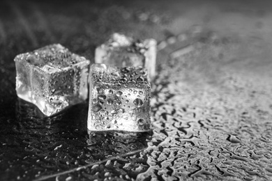 Crystal clear ice cubes on grey stone table, closeup. Space for text
