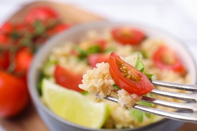 Photo of Fork with delicious quinoa salad, closeup view